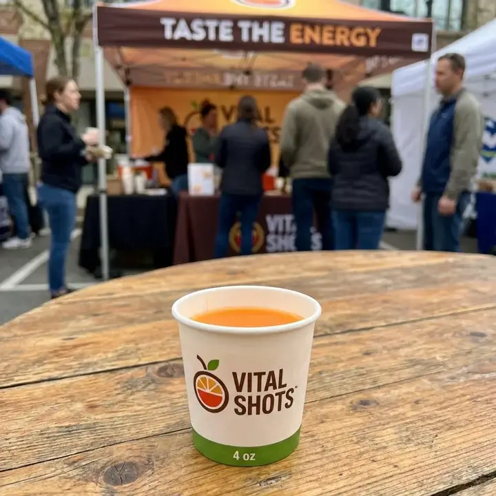 A branded 4 oz sample cup used for juice shots and promotional drink tasting at a marketing event